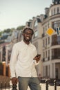 Mirthful young man in the street smiling while holding gadget