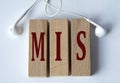 MIS - acronym on wooden blocks on white background with wired headphones