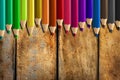 Misaligned coloured pencils on wooden desk background Royalty Free Stock Photo