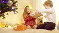 Misbehaving children fighting for New Year gift sitting in living room at home. Wide shot portrait Caucasian girl and