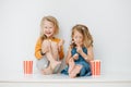 Misbehaving siblings sitting on a table with their legs up. Over white wall Royalty Free Stock Photo