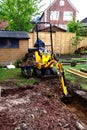 Mini digger preparing ground for foundations, UK.