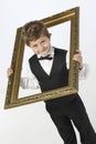 Mischievious boy looks through picture frame Royalty Free Stock Photo