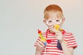 Mischievous boy playing doctor. Toy syringe, glasses and phonendoscope. Portrait Royalty Free Stock Photo