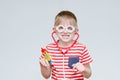 Mischievous boy playing doctor. Toy syringe, glasses and phonendoscope. Portrait Royalty Free Stock Photo