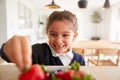 Mischievous Girl Wearing School Uniform Taking Strawberry From Kitchen Counter Royalty Free Stock Photo