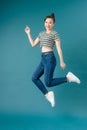 Mischievous girl wearing striped T-shirt and jeans dancing on blue background