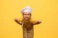 Mischievous little girl in chef's hat and apron, grimacing, making faces, posing with hands on waist, isolated on Royalty Free Stock Photo