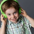 Mischievous little kid with freckles laughing, listening to music