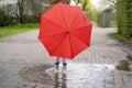 5-year-old girl in rubber boots with red umbrella stands in rain puddle, capturing pure and simple joys childhood and Royalty Free Stock Photo