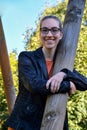 Mischievously smiling young woman clutching a wooden pole