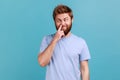 Man in blue T-shirt picking nose and sticking out tongue with dumb comical expression fooling around