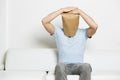 Miserable anonymous man with head covered sitting on sofa. Royalty Free Stock Photo