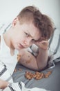 Miserable Teenage Boy in Bed Beside Pile of Vomit