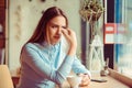 Misery, infelicity. Brunette woman girl about to cry wiping tears sneezing in a tissue drinking tea, coffee, hot beverage.