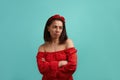 Misled disappointed european woman, brunette in red dress with bare shoulders wearing hair band looks aside, has arms Royalty Free Stock Photo