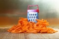 Mismatch: a small grater next to a large carrot. Cutting board on the kitchen table. Unusual mystery and optical illusion