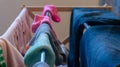 Mismatched, pair of ankle socks drying on a laundry rack with woman`s clothes including blue jeans and pink eyelet sweater, Royalty Free Stock Photo