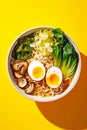 Miso ramen asian noodles soup with egg, mushrooms, and pak choi cabbage on yellow background, top view.