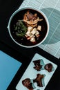 Miso soup classic with beef on blue pastel color plate at black background with sunlight and shadows, minimalism,top view