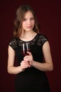 Miss in dress holding glass of wine. Close up. Dark red background Royalty Free Stock Photo