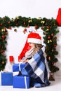 Miss Santa in red hat and blue blanket opens gift Royalty Free Stock Photo