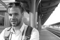 Missed train and travelling concept. Tourist with smiling face and backpack. Young man on platform Royalty Free Stock Photo