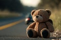 Missing child, child abuse concept. Abandoned cute teddy bear toy sitting on road on asphalt against background of leaving car
