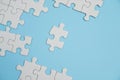 Fragment of a folded white jigsaw puzzle and a pile of uncombed puzzle elements against the background of a blue surface Royalty Free Stock Photo