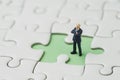 Missing key person for business success strategy concept, miniature people businessman standing at the missing white jigsaw