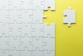 A missing piece to complete a puzzle, white pieces on a yellow textured background Royalty Free Stock Photo