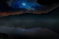 Mist hangs in montane forest on Lake reflects blue moonlight Royalty Free Stock Photo