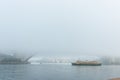 Mist shrouds Sydney harbour as ferry crosses and bridge is barely visible in morning light