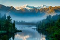 Mist at sunrise preventing the reflections of the snow capped southern alps on the calm water at Lake Matheson Royalty Free Stock Photo