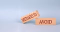 MISTAKES TO AVOID text on the wooden block, blue background Royalty Free Stock Photo