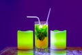 a misted glass of cold cocktail with ice, mint and straws stands on a decorative table between two glowing electric Royalty Free Stock Photo