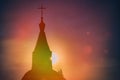 Misty beautiful sunset light of the sun illuminates catholic church. Rays of light against the black sky. Religious symbol -