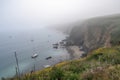 misty coastal cliff, with view of the ocean and boats in the distance