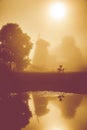 Misty dawn near water, windmill Royalty Free Stock Photo