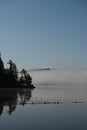 Misty foggy morning along a lake at beach front on a summer morning Royalty Free Stock Photo