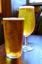 Misty glasses with two pints of cold Scotch ale, amber pale ale, lager draft beer in English pub