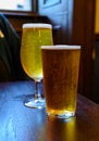 Misty glasses with two pints of cold Scotch ale, amber pale ale, lager draft beer in English pub