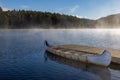 a boat dock in a misty lake with fog rising in the sky Royalty Free Stock Photo