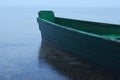 Misty morning on the lake. Green boat moored to the shore Royalty Free Stock Photo