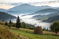 Misty mountain landscape with fog and haystack Royalty Free Stock Photo