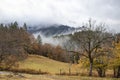 Misty mountains - open field and fence with trees and fog on the mountians in the background in autumn