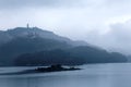 Misty mountains by Sun Moon Lake on a foggy morning, with a pagoda on the distant mountaintop under moody cloudy sky Royalty Free Stock Photo