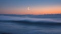 Misty Ocean Wave at Sunset with Crescent Moon Royalty Free Stock Photo