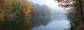 Misty panorama of colorful autumn trees reflecting in the still river water Royalty Free Stock Photo