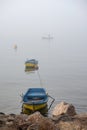 Misty Rocky Coastline with Tethered Boats and a Lone Fisherman